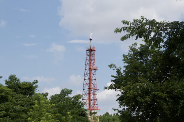 Flare stack at oil refinery tank farm.